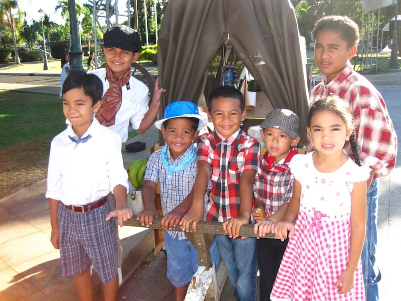 Children in Tahiti smile while pulling a replica of a covered wagon at a Pioneer Day celebration in Tahiti, July 2010. Michael Moody — composer of "I'm a Pioneer Too" — and his wife, Maria Moody, attended the celebration.