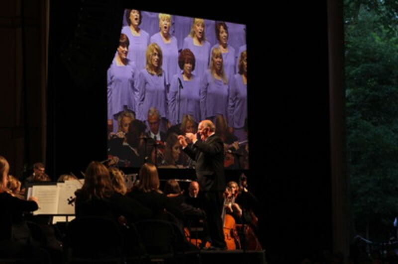 With an image of singers on screen in background, Mack Wilberg directs the Tabernacle Choir in conce