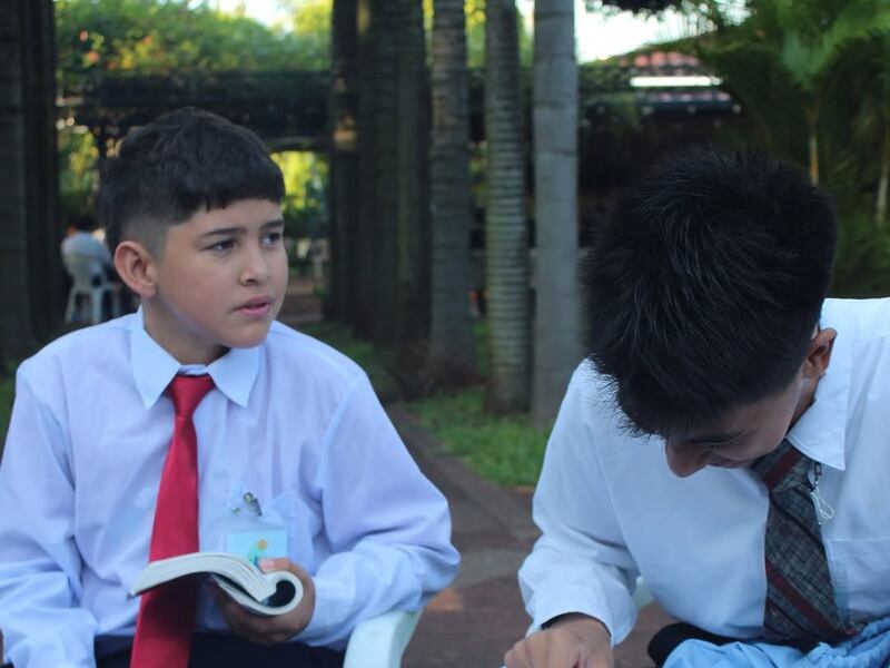 Two young men study the scriptures at a For the Strength of Youth conference in Paraguay in January 2026.