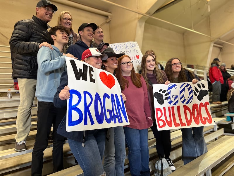 Members of young single adult ward in Fresno, California, hold signs as they cheer on Brogan Hill, center, at a Fresno State meet in February 2024.