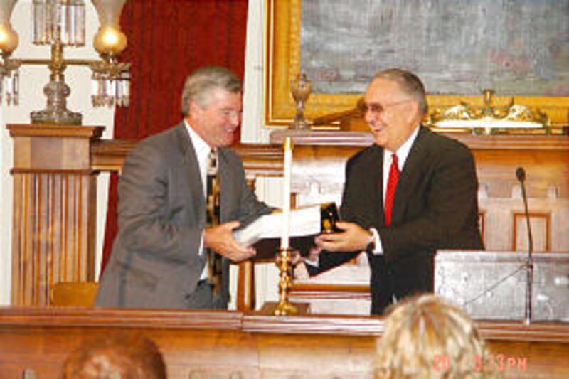 Mayor Timothy J. Davlin accepts family history from stake President Alonzo J. Mackelprang.
