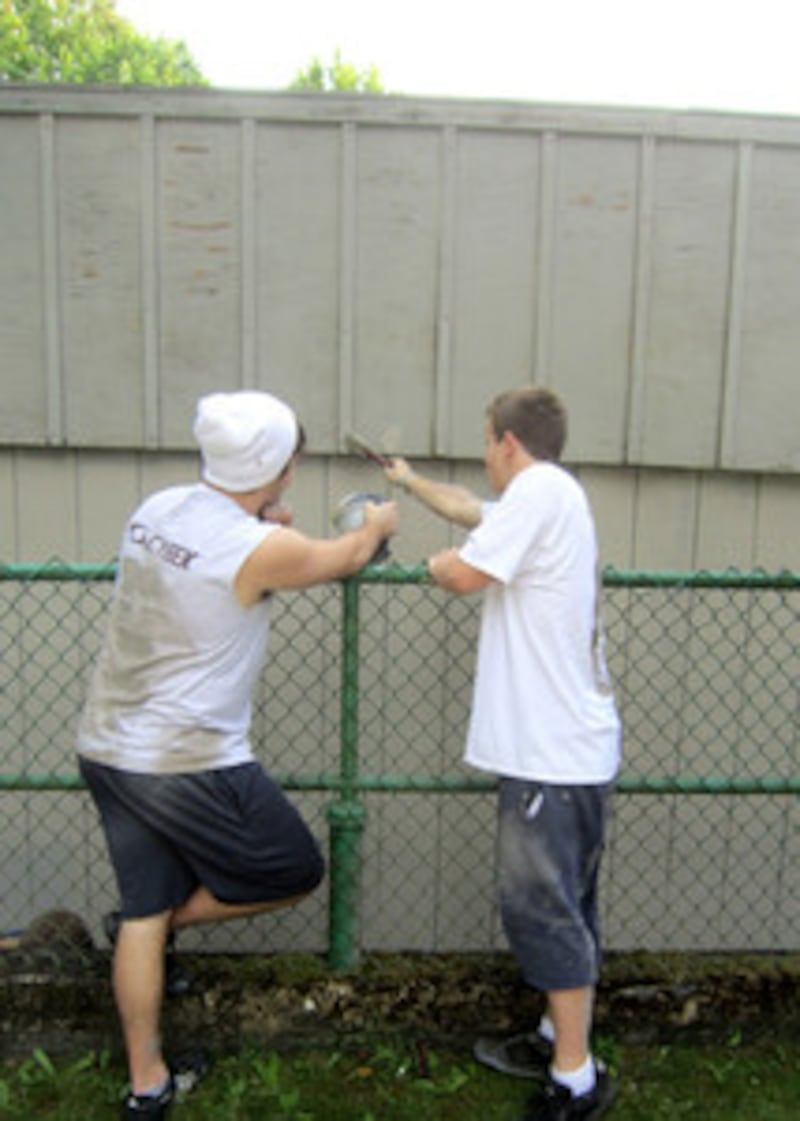 Teens touch up a fence with some paint in lake Stevens, Washington.