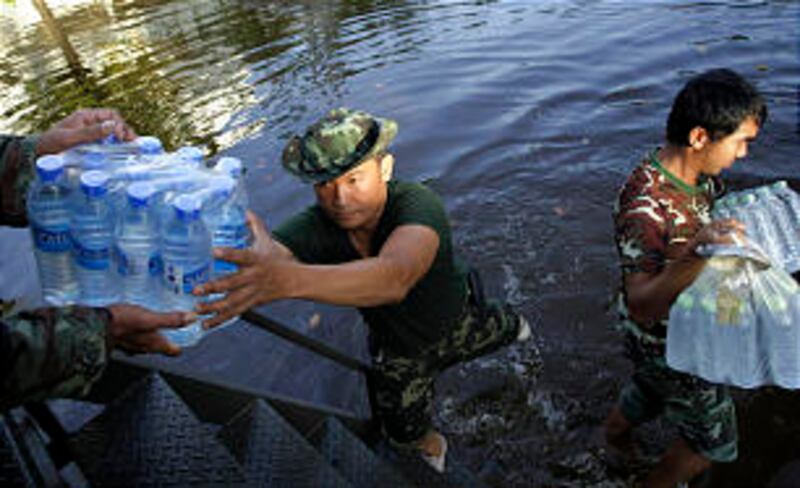 Thai soldiers deliver bottled water for flood victims to an evacuation center in Bangkhunthian distr