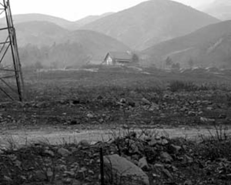 Blackened acres surround home of Ty and Loni Larson, which was spared destruction by fire.
