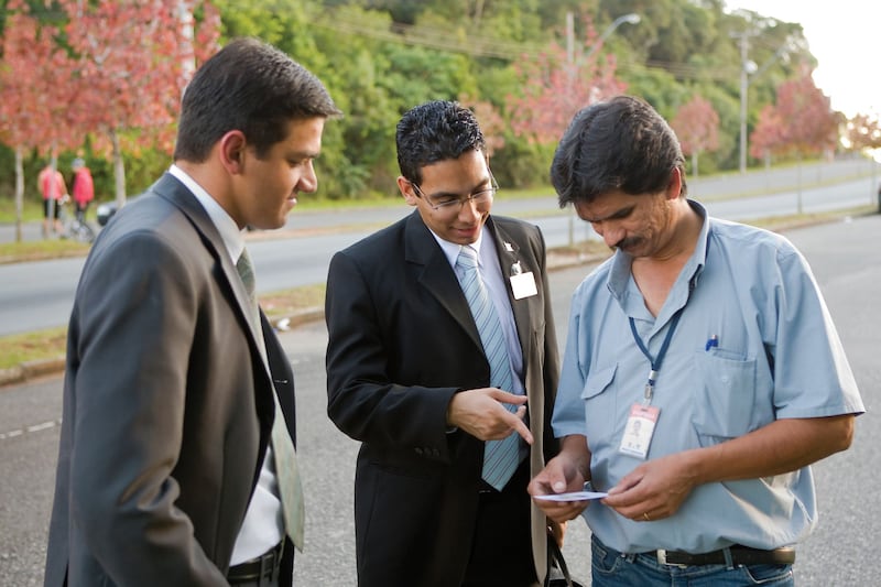 Missionaries of The Church of Jesus Christ of Latter-day Saints in Brazil give a passalong card to a man.