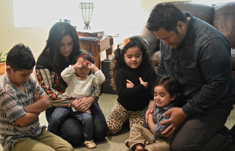 A family prays together in a home.