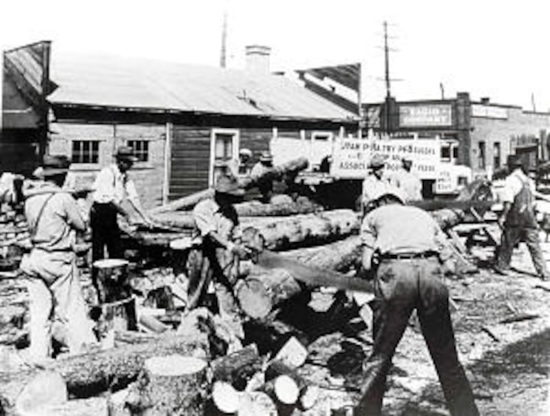 Men work in 1930s lumber yard to cut firewood to help the needy and themselves during Depression.