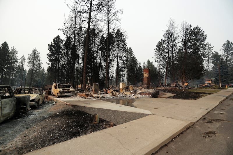 Debris is strewn around burned structures after a wildfire, Sunday, Aug. 2, 2026, in Spokane, Washington.