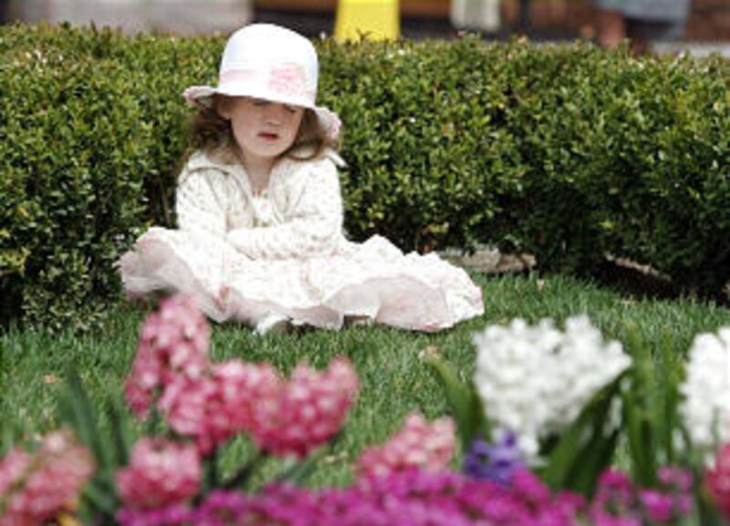Blaire Gibson, 2, from Ogden, Utah, sits on the grass on Temple Square and folds her arms during the