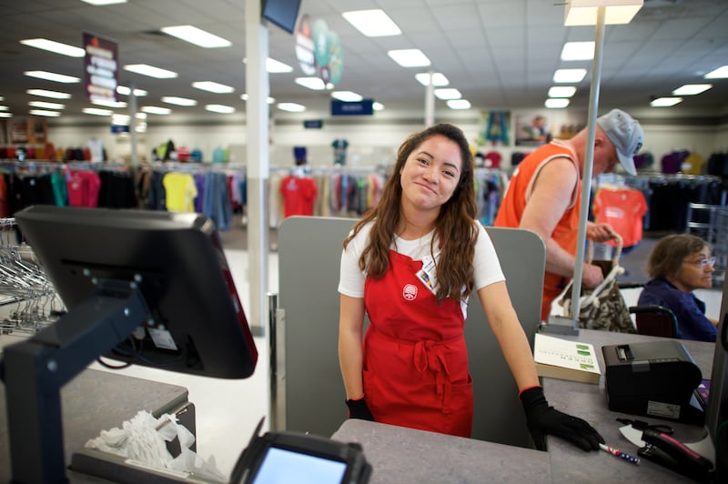 A Deseret Industries associate smiles while working at the cash register.