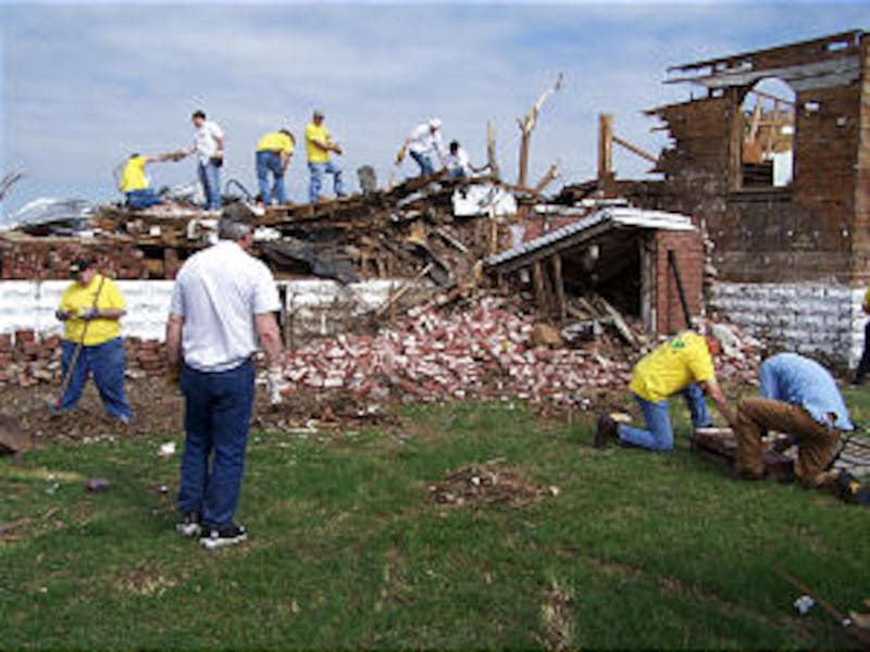 Church members, most in yellow t-shirts, helping clean up debris of antique store owned by Church me
