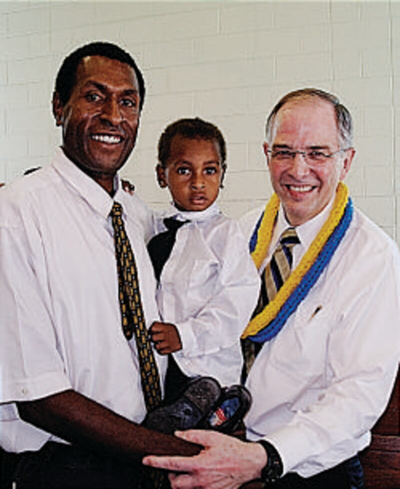 Elder Neil L. Andersen stands with a member and his son while visiting Papua New Guinea in January.