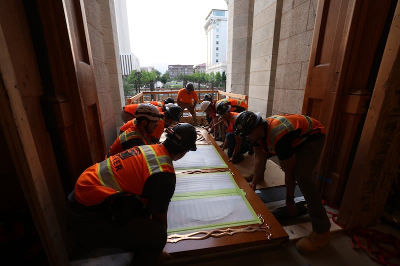 Workers prepare to hoist the east door of the Salt Lake Temple into place on Tuesday, June 23, 2026.