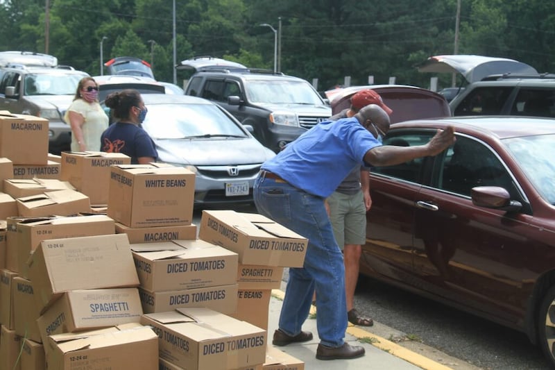 Woodbridge Virginia Stake President David Oryang, in blue shirt, greets people receiving food during stake-coordinated food drive.
