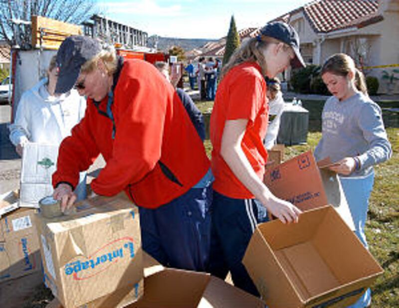 Young women and their leaders fold and tape boxes to be used to store household items.