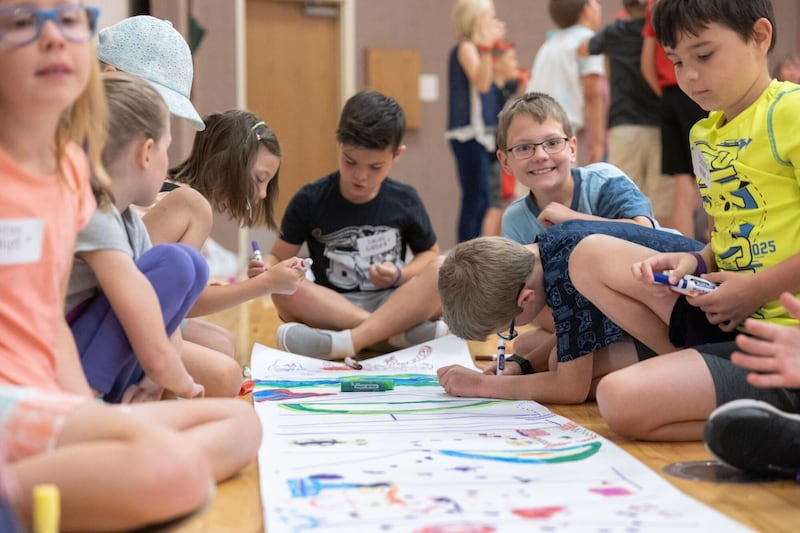 Lucas Gifford, 8, looks up and smiles as a group of children draw a poster