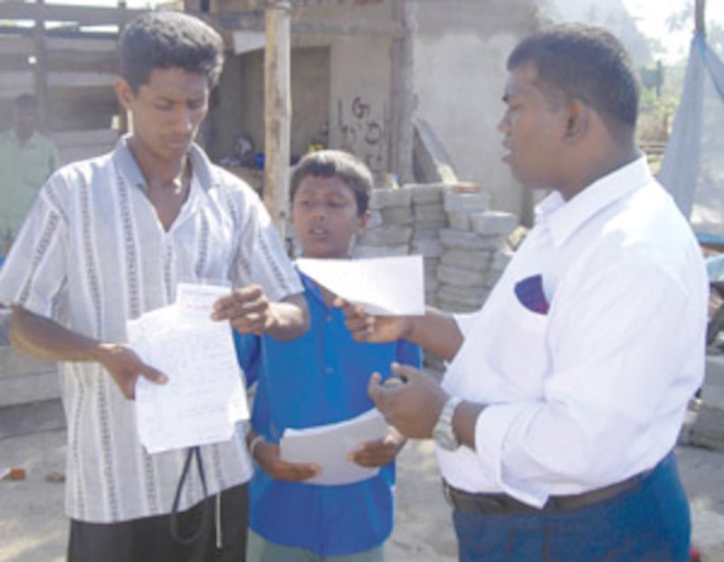 Village chief, left, in Sri Lanka temporary village reviews, with branch president, papers listing i