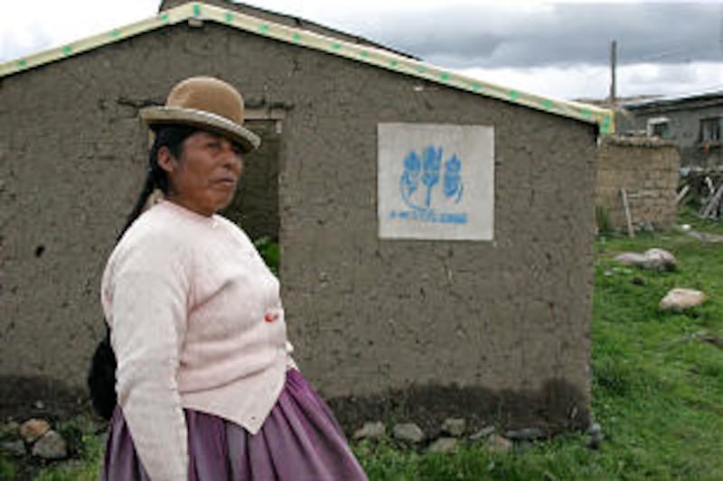 An indigenous Bolivian woman outside her above-ground greenhouse that was built with the assistance