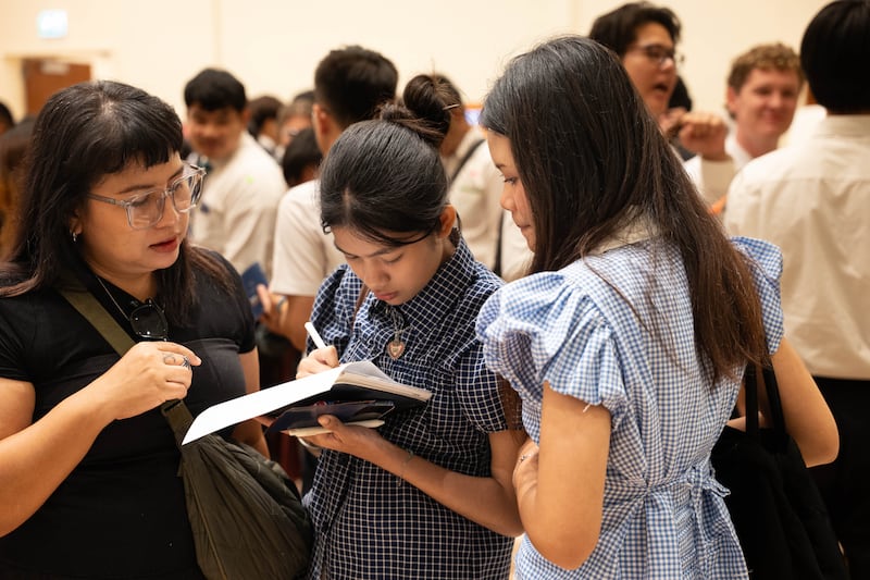 Supavadee Kasinsri and her daughter take notes to navigate the Asia Area education fair booths in Bangkok, Thailand, on Oct. 19, 2025.