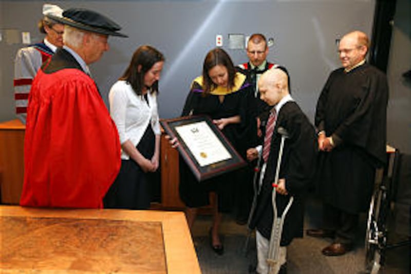 11-year-old Malachi Ray, center right, receives a certificate from registrar Asa Kachan recognizing