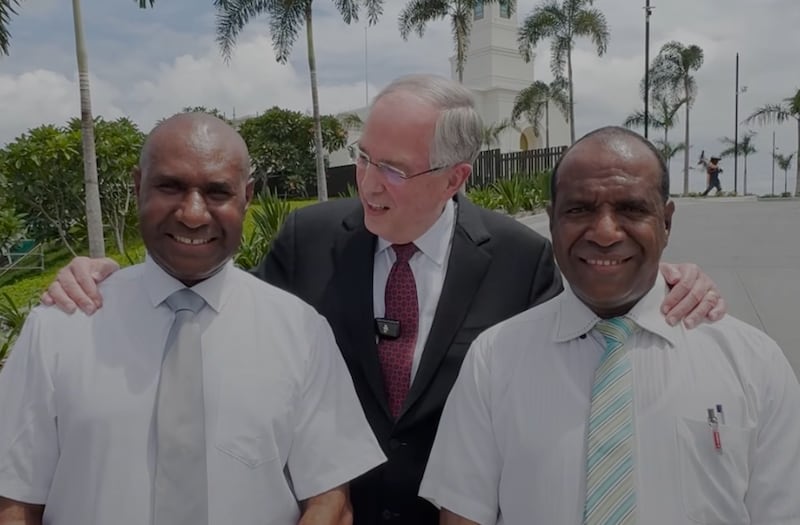 Elder Neil L. Andersen stands with two men in a social media post on March 13, 2026.
