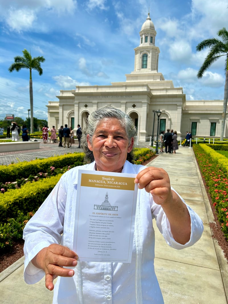 Betty Antonia Castro Torres holds up a card with the words to the hymn, "The Spirit of God Like a Fire is Burning," outside the Managua Nicaragua Temple after the dedication in Managua, Nicaragua, on Sunday, Oct. 18, 2026.