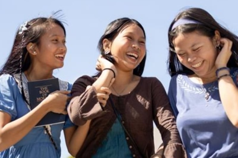 Three young women speak together outside.