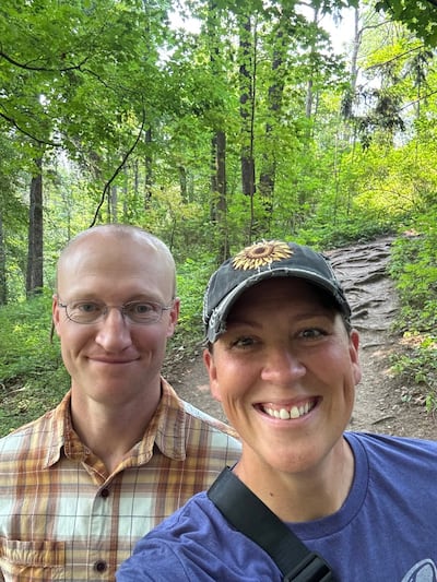 Glenn and Erica Nielson stand outside together in front of a dirt trail.