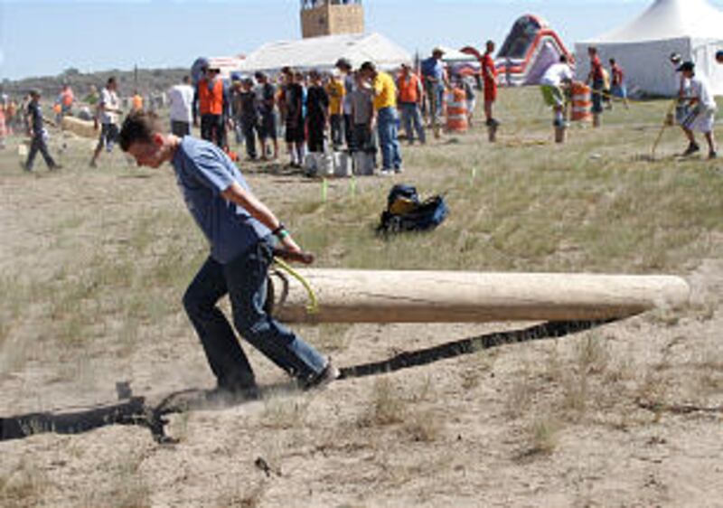 Young man utilizes all his strength to move a large log at the 2013 Rise Up Scout Camp.