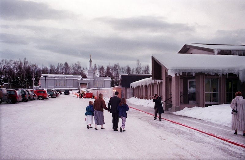 With the Anchorage Alaska Temple in the background and the adjacent meetinghouse to the right, a family is photographed arriving for the temple's dedication on Jan. 9, 1999, in Anchorage, Alaska.