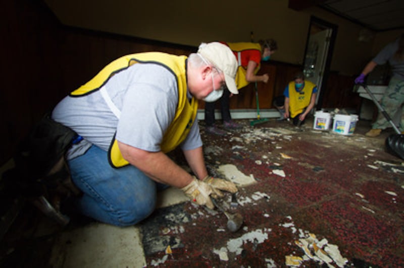 Members assist in removing damaged floor tile.