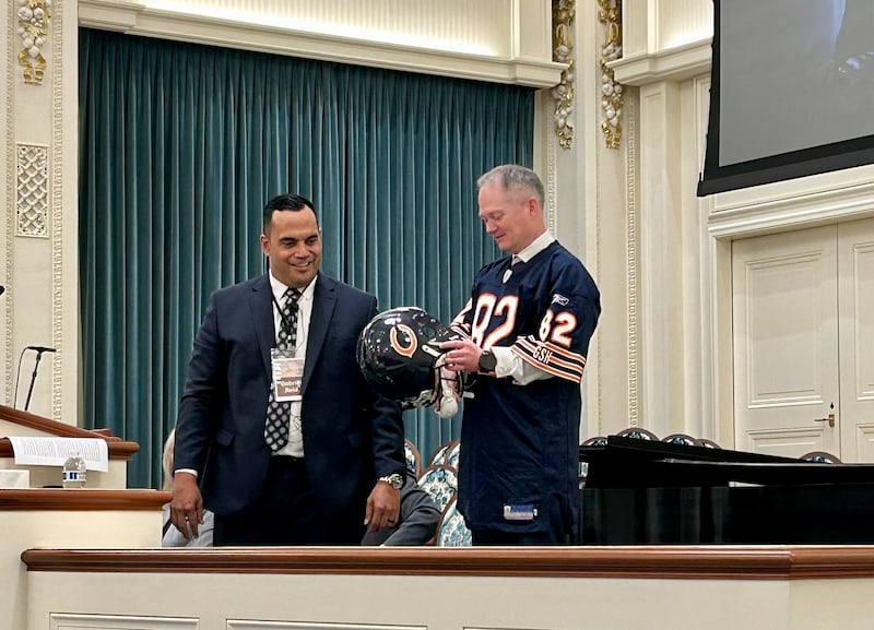 Brother Gabriel Reid, second counselor in the Sunday School general presidency, left, dresses C. Todd Linton, director of the Church’s Military Relations, Chaplain Services and Prison Ministries Division of the Priesthood and Family Department, in his old Chicago Bears jersey and helmet during Brother Reid's presentation at the 2026 Chaplain Training Center at the Joseph Smith Memorial Building in Salt Lake City, Utah, on Oct. 6, 2026.