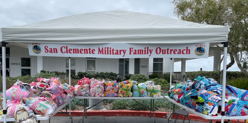 Hundreds of baby supplies line tables under a San Clemente Military Family Outreach sign before a baby shower for Camp Pendleton military moms in California