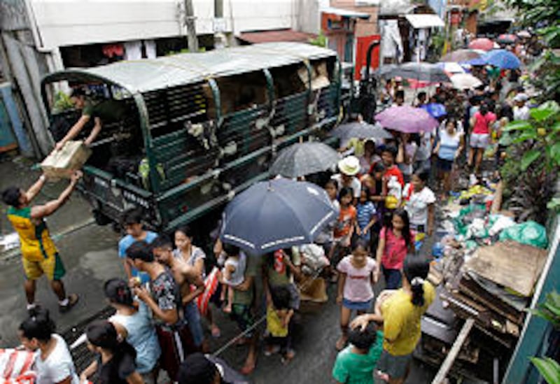 Residents queue for relief goods in a hard-hit residential area in suburban Quezon City, north of Ma