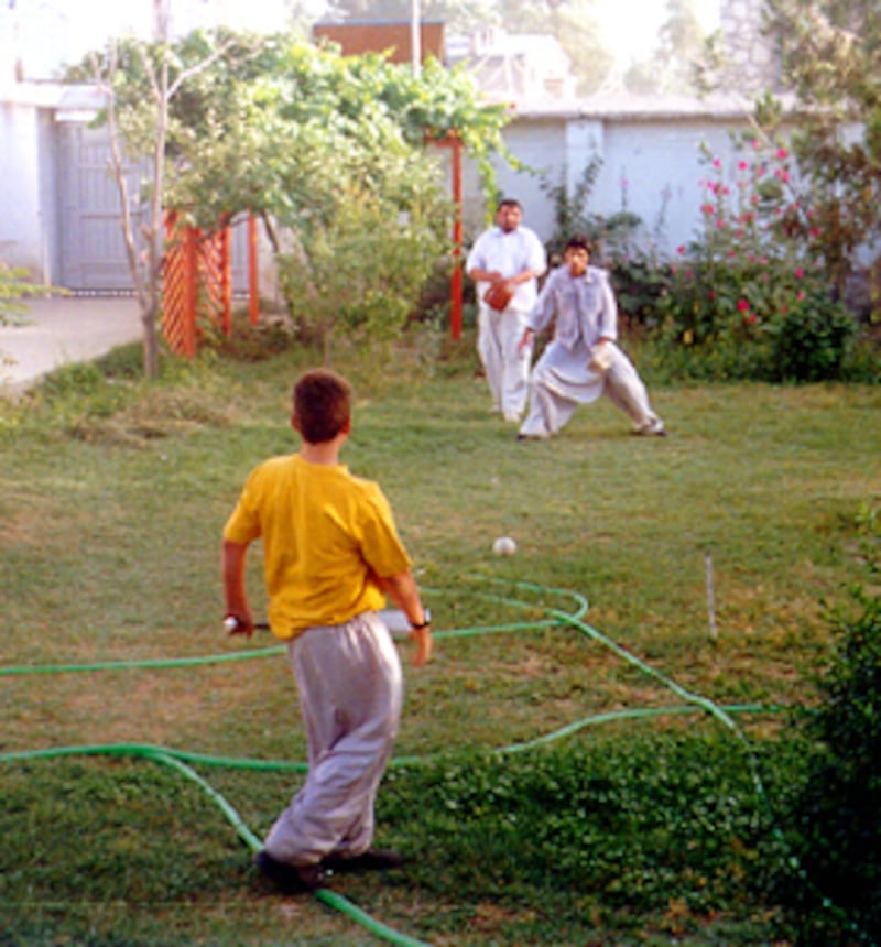 Ben Inks hits baseball to two Afghan house boys in Afghanistan.