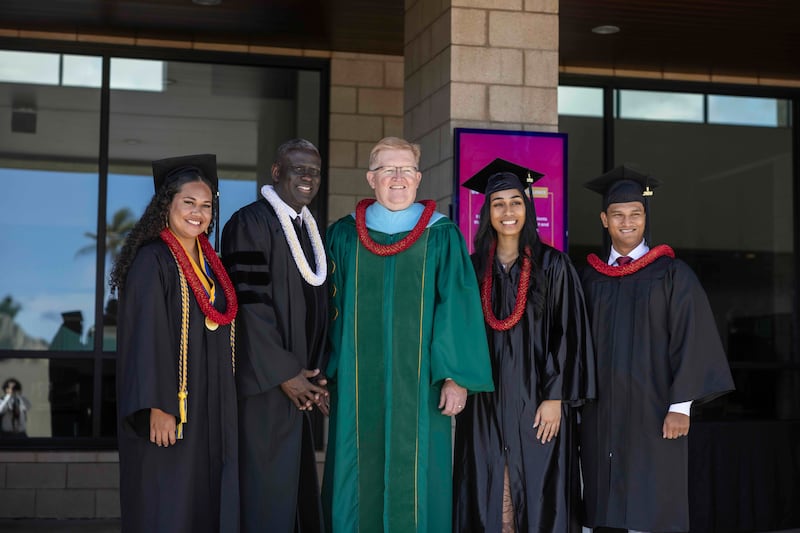 Elder Peter M. Johnson, a General Authority Seventy, second from left, and BYU–Hawaii Acting President R. Kelly Haws, center, pose for a photo with graduates on Friday, April 17, 2026.