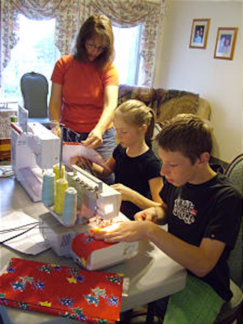 Julie Crosgrove helps her children Brianna, 11, and Spencer, 13, sew the travel bags together for ch