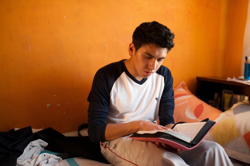 A young Latter-day Saint in Bolivia reads the scriptures in his bedroom.