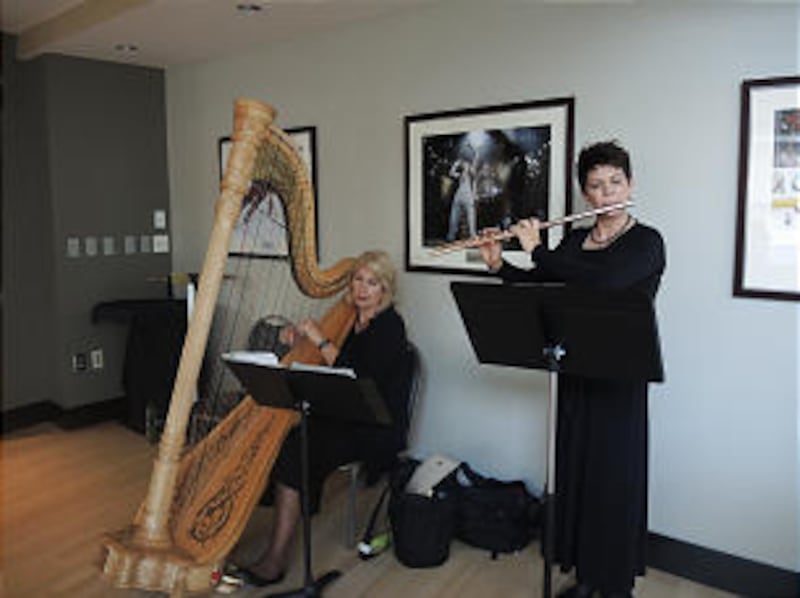 Tamara Oswald, left, and Jeannine Goeckeritz play harp and flute during a reception for guests prior