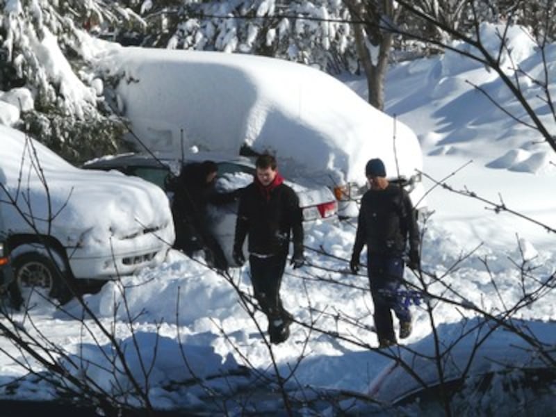 Elder Stephen Sowby (right) and a neighbor worked to dig out snow around cars in the parking lot whe