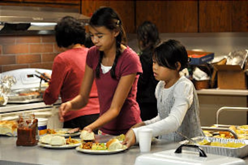 Ester Yuen, left, and Audrey Yuen help prepare dinner for the Christmas social of the new Yale Chine