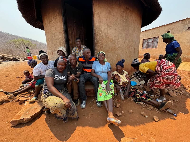 Kilford Shereni, center, sits with family and friends at the family kamusha — meaning “home” or “origin” in the Shona language.