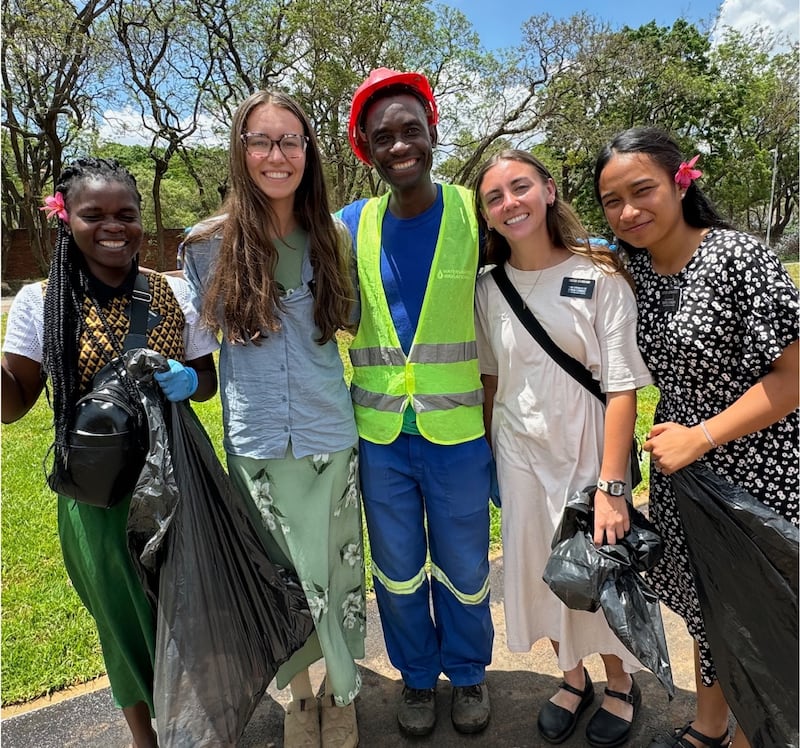 Kilford Shereni pauses from his work on the Harare Zimbabwe Temple grounds to join sister missionaries picking up trash.