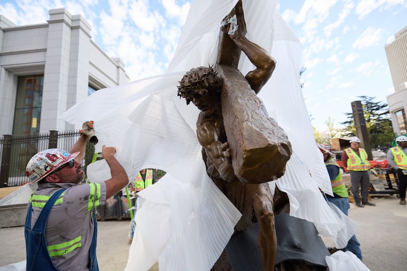 Crew members install the “Jesus Christ Carrying the Cross” statue, created by Michael Hall, just south of the Salt Lake Temple on Wednesday, Sept. 17, 2025.