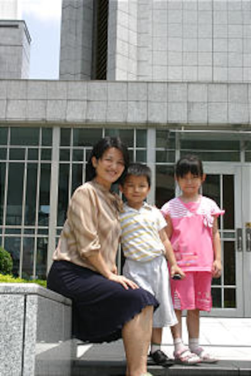 Sister Peng Mei Zhu Hsu of the Chi An Branch on Taiwan's east coast sits by temple with her children