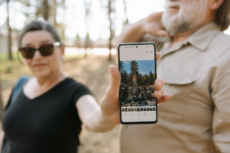 Cherie Tolman holds up a picture showing what remains of their home after it was destroyed in the Spokane wildfires in early August in Spokane, Washington, on Saturday, Aug. 22, 2026.