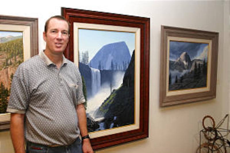 Mark Gudmundsen stands next to some of the paintings of landscapes from the natural setting where he