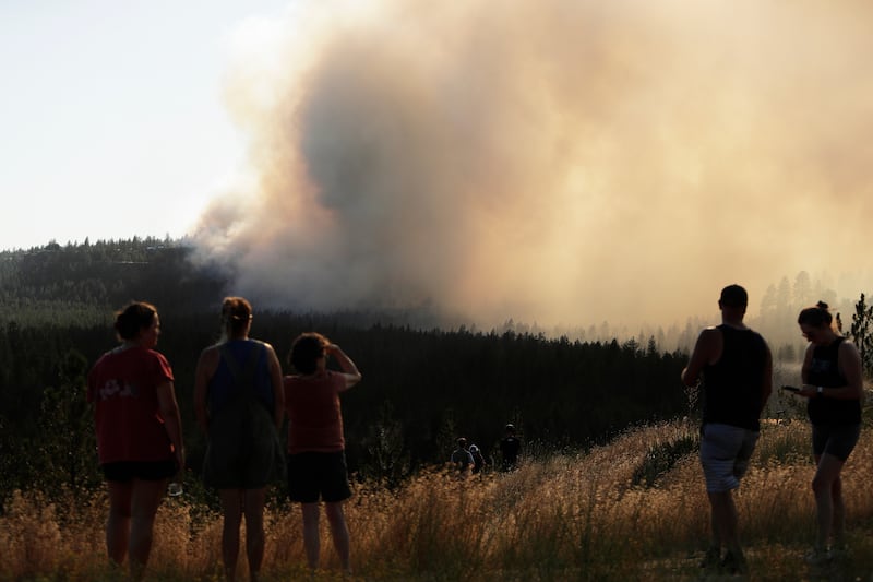 People watch Old Trails Fire from W. Northwest Blvd., Saturday, Aug. 1, 2026, in Spokane, Washington.