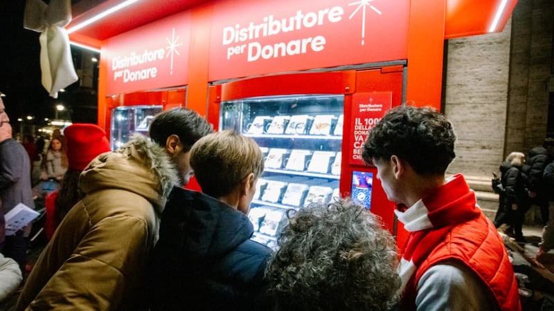 A volunteer assists guests as they choose an item to donate using the Giving Machine donation vending machines in Rome, Italy, on Monday, Dec. 8, 2025.