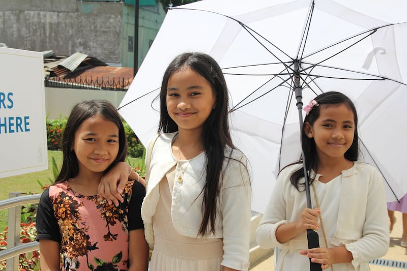 Three girls smile for a picture outside the Davao Philippines Temple on the last day of the public open house, April 10, 2026.